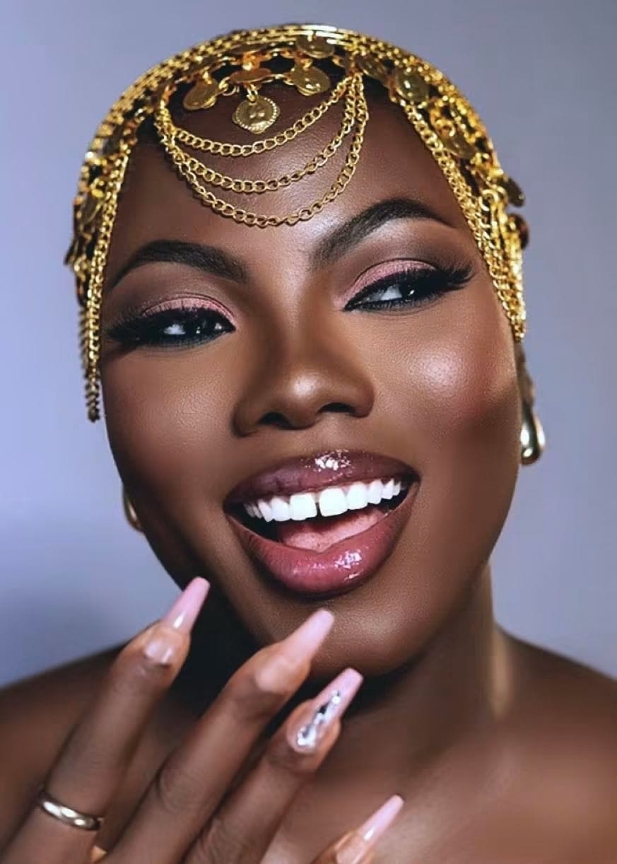 A laughing woman in a gold chain headpiece